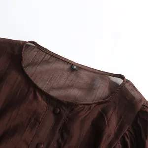 Close-up detail of the round neckline and brown pleated fabric texture on a palace style dress