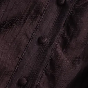 Macro detail of dark brown dress fabric texture and fabric-covered buttons.