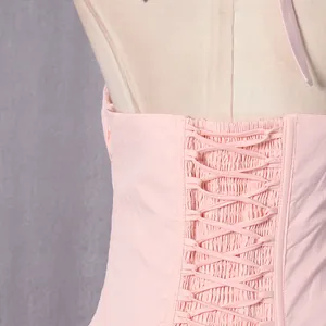 Detailed macro view of the adjustable lace-up back and smocked bodice of this pink dress