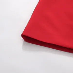 Macro detail of the smooth red fabric and clean hemline of a stylish solid color dress