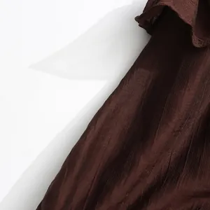 Detailed close-up shot showing the textured brown fabric and ruffle of this elegant dress