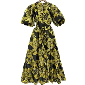 Close-up detail shot of an elegant yellow floral maxi dress with puff sleeves and tie waist