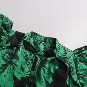 Detail shot of a green and black floral printed dress with puff sleeves and buttons.