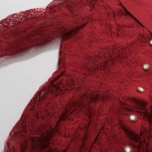 Detailansicht eines roten Kleides mit Stickerei-Spitze und Perlenknöpfen im französischen Stil.