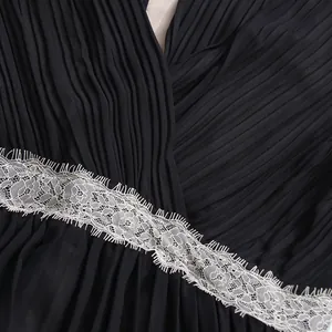 Gros plan d'une robe plissée vintage française avec d'élégantes finitions en dentelle blanche.