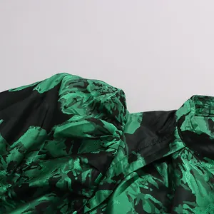 Detailed macro view of green floral print puff sleeve dress showing fabric texture