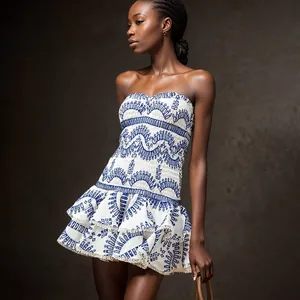 Detailweergave van witte strapless jurk met blauw borduursel en ruches aan de zoom.