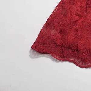 Nahaufnahme einer roten Spitzenstickerei mit Wellenkanten und feinen floralen Mustern