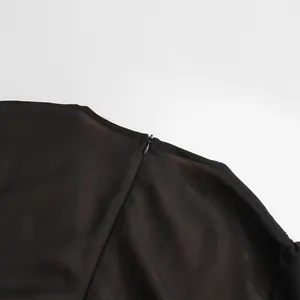Détail d'une fermeture éclair invisible sur une robe noire rétro française plissée.