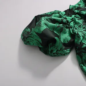 Detailed close-up of the green and black floral print puff sleeve on a satin dress