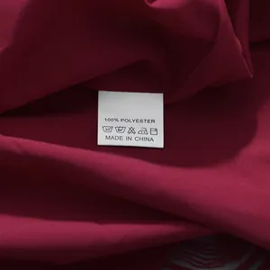 Detailaufnahme des Pflegeetiketts eines burgunderfarbenen Kleides, 100% Polyester