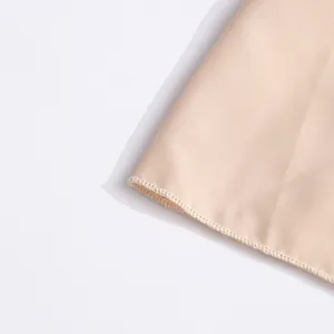 Gros plan détaillé montrant l'ourlet à points de surjet sur un tissu en satin champagne