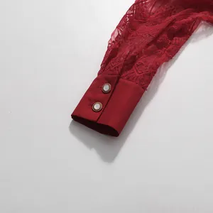 Detailansicht des Ärmels eines roten Spitzenkleids mit eleganten Schmuckknöpfen.