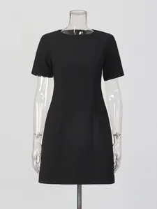 Elegante abito corto nero con girocollo e maniche corte, design sciancrato chic.