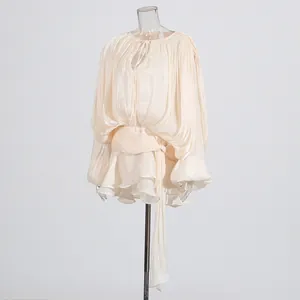 Detail view of cream pleated mini dress with lantern sleeves and ruffled hem design
