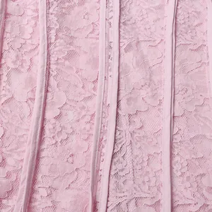 Macro view showing the intricate floral lace pattern and pink fabric texture of the dress