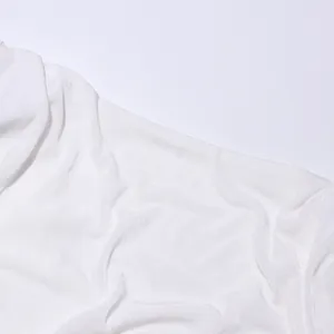 Nahaufnahme der schimmernden weißen Stofftextur eines eleganten langärmeligen Abendkleides