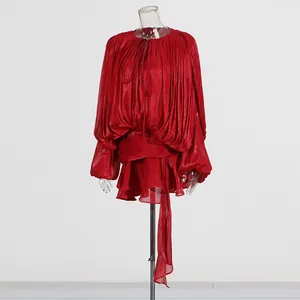 Detailed view of a stylish red pleated mini dress with puff sleeves and ruffle hem