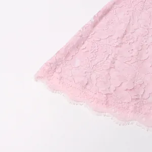 High-quality macro shot of pink floral lace fabric showing delicate eyelash fringe detail.