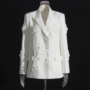 Dettaglio di un blazer bianco con intricate applicazioni floreali 3D su davanti e maniche.