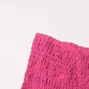 Macro-detailopname van magenta gesmokte stof met borduursel op een rok met ruches