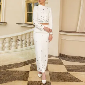 Full view of white rhinestone two-piece set against classical architecture background