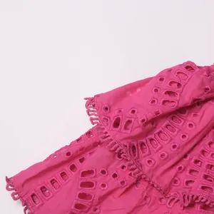 Detail van fuchsia oogje borduurwerk en ruches op een stijlvolle zomerjurk