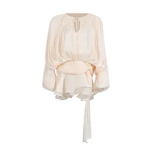 Close-up of pleated champagne mini dress with puff sleeves and tie waist detail.