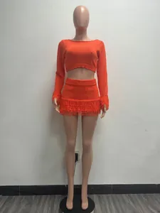 Orange two-piece knit set featuring a long-sleeve crop top and fringe mini skirt