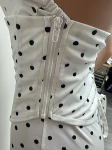 Détail rapproché d'une combinaison à pois noir et blanc avec fermeture à glissière.