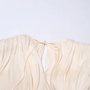 Detailed close-up of the elegant tie-up neckline on a pleated cream shimmer dress