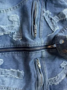 Close-up detail of blue distressed denim jacket with multiple zippers and frayed edges