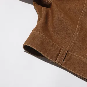 Dettaglio ravvicinato del tessuto in twill marrone vintage con cuciture bianche sulla giacca
