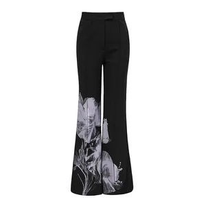 High-waisted black flared trousers featuring an elegant greyish floral print at the bottom