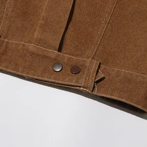 Primo piano dell'orlo di una giacca di jeans marrone retrò con bottoni e cuciture bianche