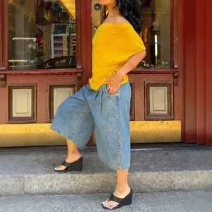 Close-up street view of stylish denim wide-leg pants paired with yellow top detail