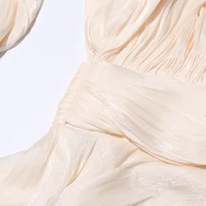 Close-up detail of pleated cream fabric with elegant shimmering finish on designer dress