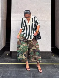 Full-length view of woman wearing street style camouflage wide-leg pants in urban setting