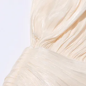 Close-up view of the delicate pleated texture and invisible zipper on a cream dress