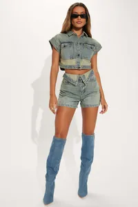 Model wearing trendy two-piece denim set with cropped jacket and V-waist shorts