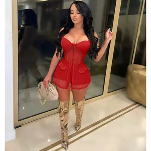 Model in einem roten zweiteiligen Set aus Mesh-Corsagen-Top und Shorts mit Goldstiefeln.