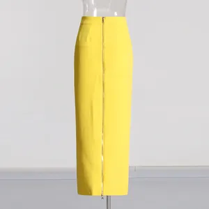 Detail view of a yellow high-waisted pencil skirt with a vertical front golden zipper