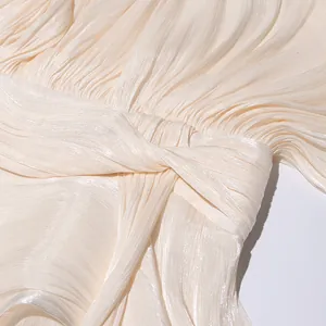 Close-up detail of pleated texture and elegant knotted waist design on champagne dress