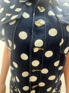 Close-up of denim shirt set featuring large white polka dots and silver metal buttons