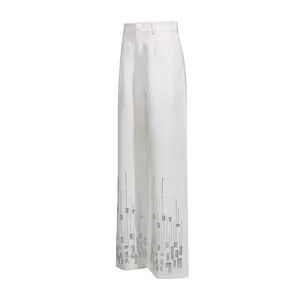 Detail of white wide-leg trousers featuring sparkling silver sequin hem embellishments.