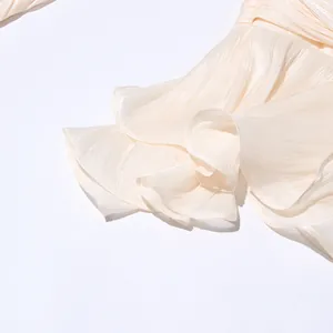 Detailed view of cream pleated flounce sleeve with shimmery textured fabric finish