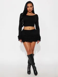 Chic black two-piece knit set featuring a long-sleeve crop top and fringe hem mini skirt
