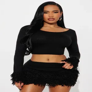 Detail view of a black two-piece knit set featuring long sleeves and heavy fringe trim