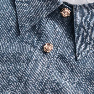 Macrodetail van de gouden metalen knopen met reliëf op de kraag van een denim shirt