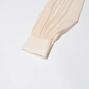 Close-up macro detail of pleated cuff on a cream-colored elegant chiffon dress sleeve.